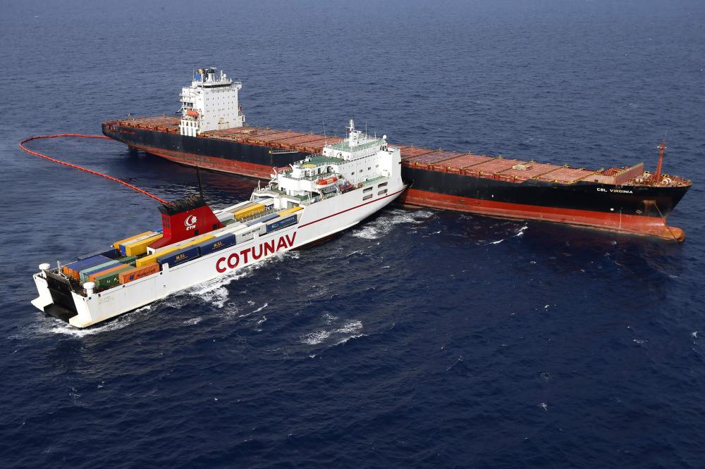 TOPSHOT - Aerial view taken from an helicopter on October 10, 2018 shows two cargo ships - the Tunisian freighter Ulysse (L) and the Cyprus-based vessel anchored CLS Virginia - after they collided about 30 kilometres (20 miles) off the northern tip of the French Mediterranean island of Corsica on October 7, 2018. - French and Italian civil and military teams were working to contain a spreading oil spill in the Mediterranean after a container ship collision off the island of Corsica that prompted France to launch an investigation into 