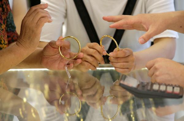 عملاء يختارون الأساور الذهبية في متجر مجوهرات في بكين - رويترز