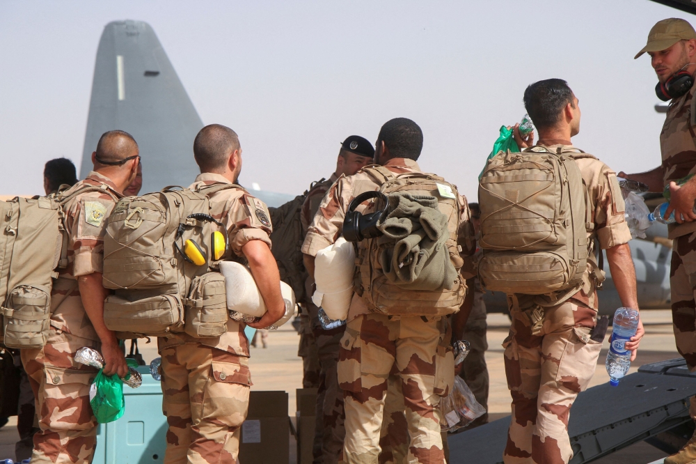 جنود من آخر القوات الفرنسية في النيجر يستعدون للصعود على متن طائرة عسكرية- رويترز 