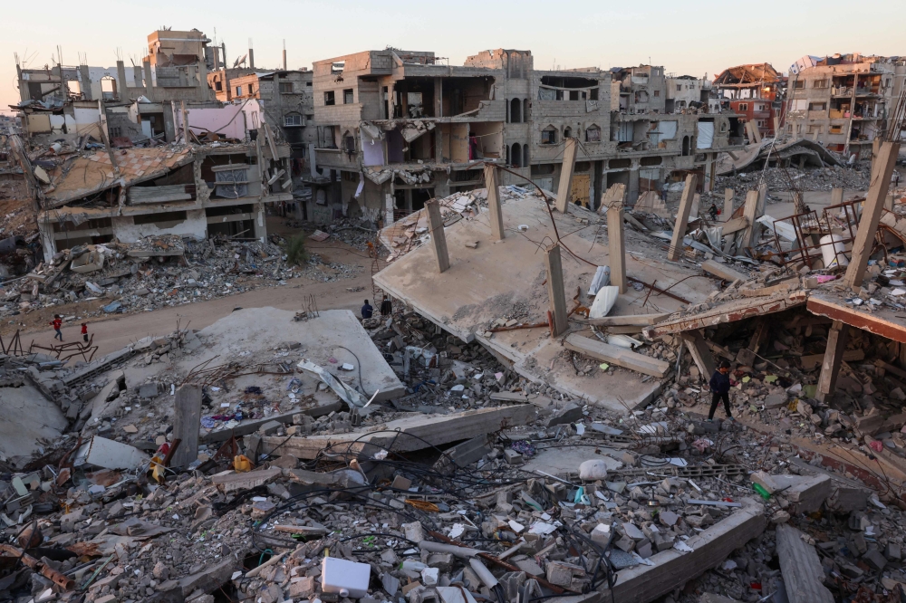 فلسطينيون يسيرون في حي مدمر بسبب الضربات الإسرائيلية- أ ف ب