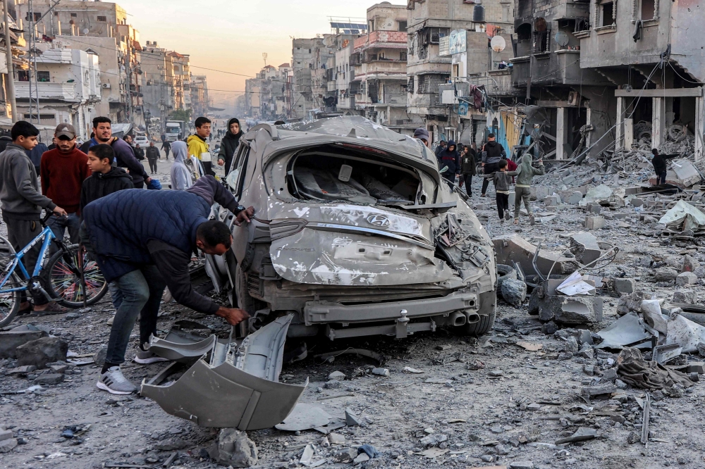 أشخاص يتفقدون الحطام والأنقاض بموقع القصف الإسرائيلي في غزة- أ ف ب