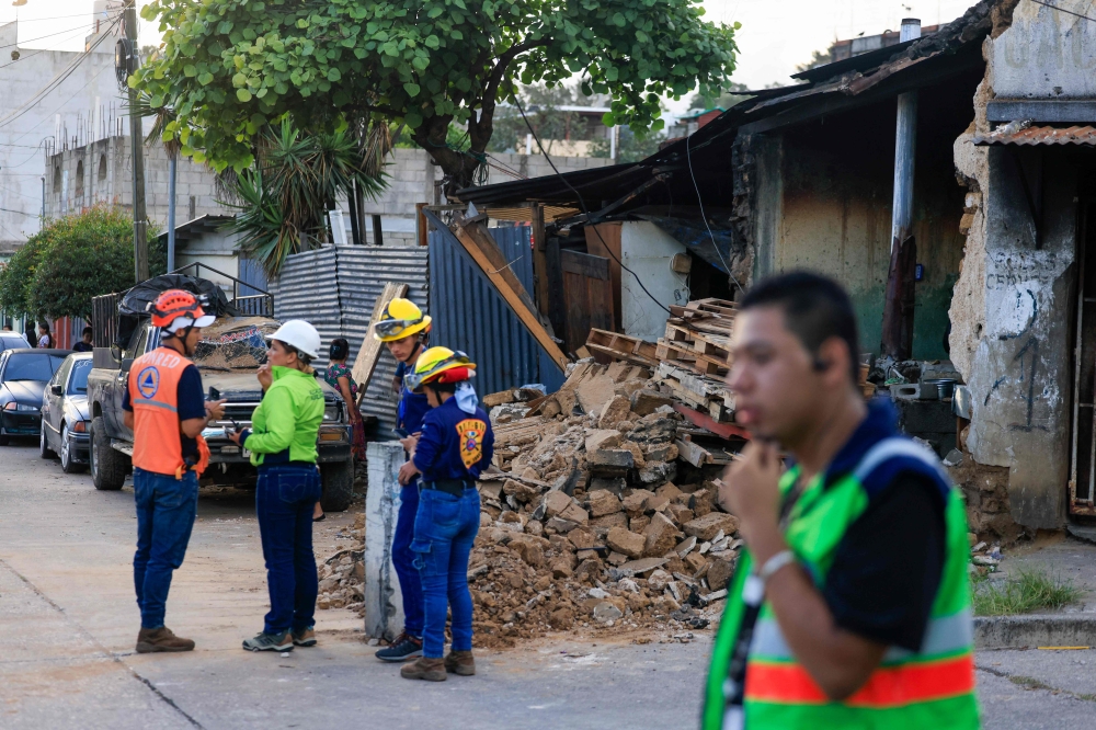 يقف رجال الإطفاء وأفراد الحماية المدنية أمام منزل منهار - أ ف ب