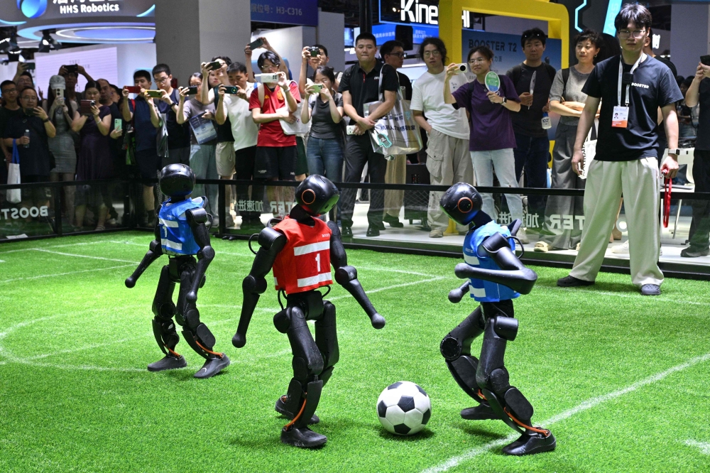 Humanoid robots from Booster Robotics play football during the World Artificial Intelligence Conference (WAIC) in Shanghai on July 18, 2026. (Photo by Hector RETAMAL / AFP)