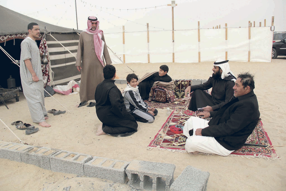 أفراد عائلتي العرفج والعمير مستمتعون بالجلوس أمام المخيم (تصوير: محمد نصر)