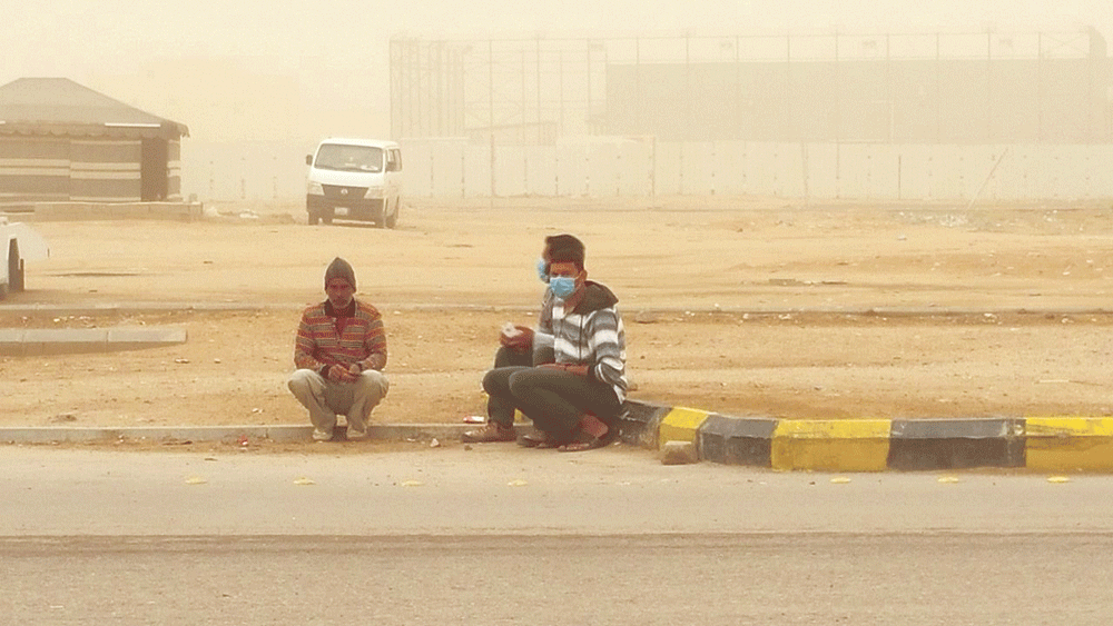 عمالة تجلس على طرف شارع وسط الغبار (تصوير: منيس الشيحي) 