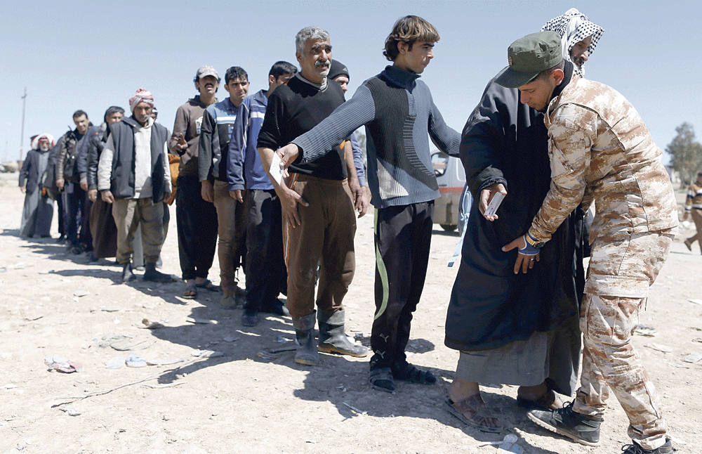 فحص العراقيين الفارين من قتال الموصل لدى وصولهم إلى المخيمات (أ.ف.ب)