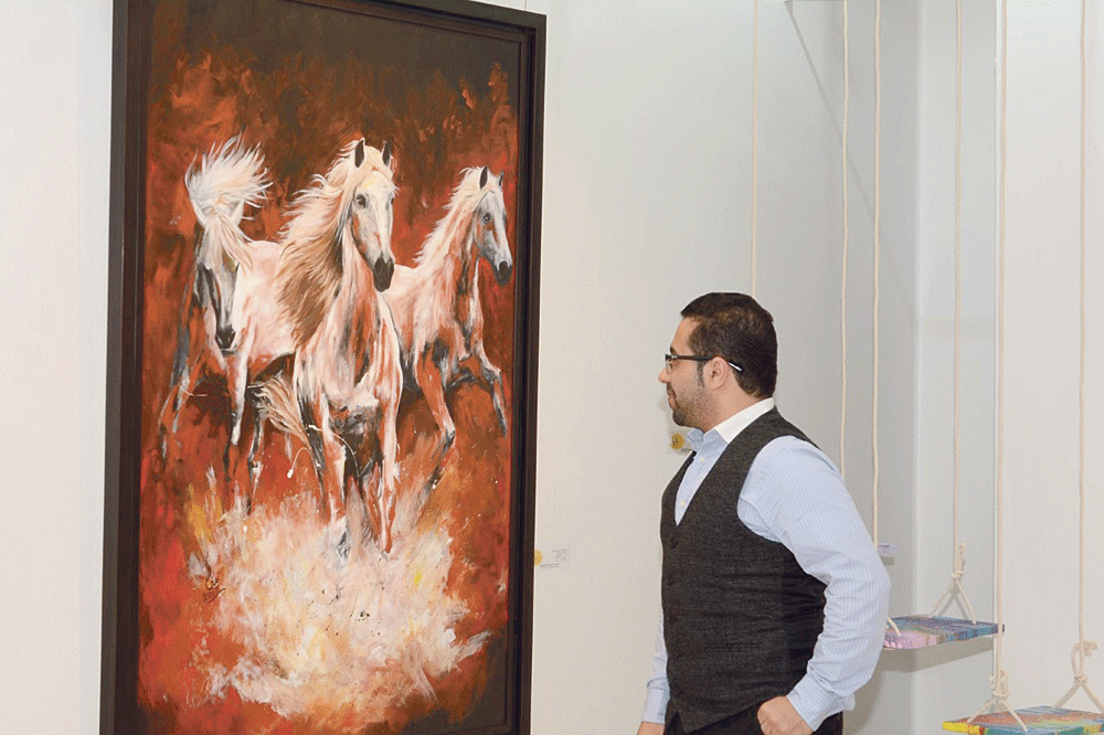 زائر يتأمل إحدى اللوحات (تصوير: بندر الشاخوري)