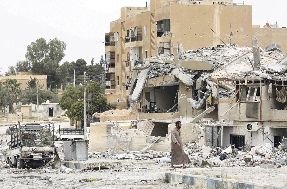 سوري يمشي أمام مبان مدمرة في بلدة الطبقة غرب مدينة الرقة (أ.ف.ب)
