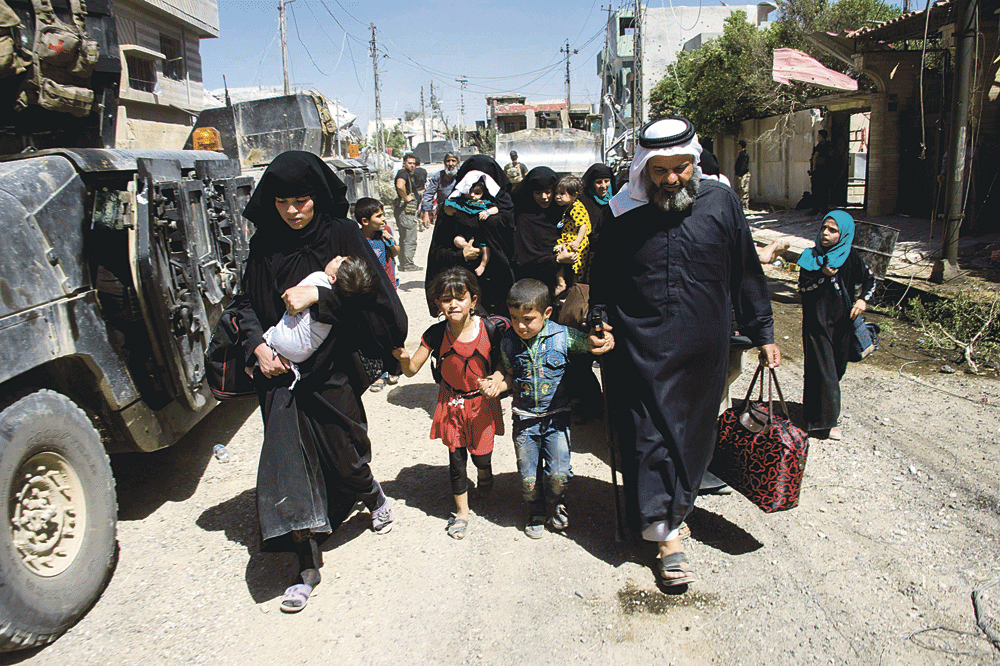 عراقيون يغادرون منازلهم مع اتخاذ أفراد من الجيش موقعا بالموصل (أ.ف.ب)