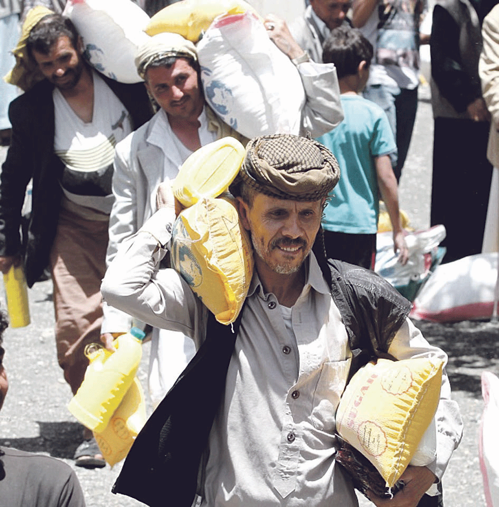 يمنيون يحصلون على حصص غذائية من جمعية محلية في صنعاء (إ.ب.أ)