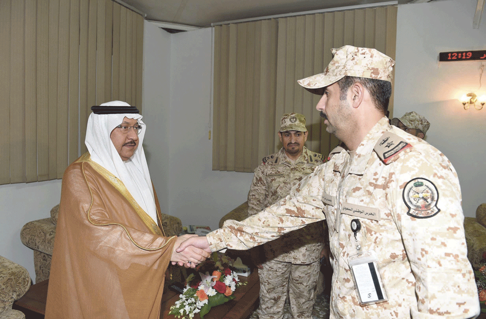 الأمير خالد بن فيصل يصافح أحد الضباط (واس)