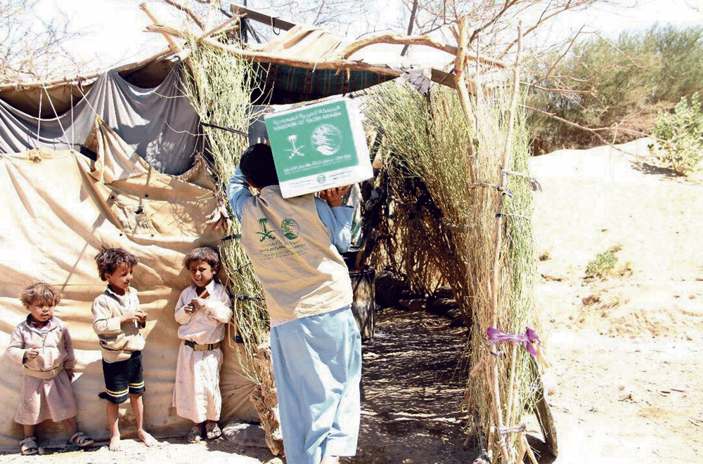 موظف يحمل حصة أسرة نازحة بمحيط صنعاء