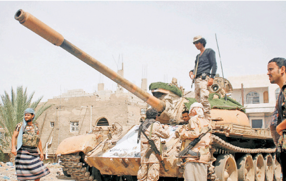 جنود من قوات الشرعية يقفون بجانب دبابة في قتالهم ضد الانقلابيين في تعز (رويترز)
