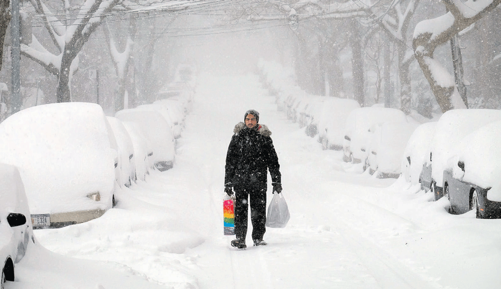 رجل يشق طريقه بصعوبة وسط الشوارع التي غطتها الثلوج